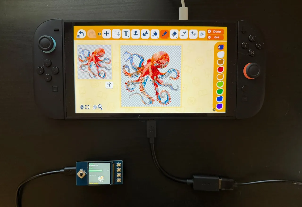 A picture of a Nintendo Switch 2 on a desk showing Tomodachi Life: Living the Dream's image editor. A Raspberry Pi Pico with a small screen and buttons attached is plugged into the bottom USB port. An image of an octopus is being drawn on the Switch 2 by the Pico, which is displaying a thumbnail and progress bar.